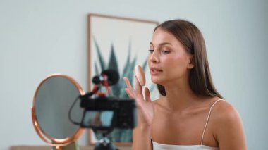 Sosyal medya için güzellik ve kozmetik video içeriği hazırlayan genç bir kadın. Güzellik blogcusu kameraya gülümserken seyircilere ve takipçilere güzellik bakımını gösteriyor. Düzenle