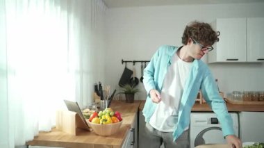 Mutlu baba yemek pişirirken müziğe geçiyor ve modern mutfakta öğle yemeği hazırlıyor. Aktif baba, sebze ve mutfak gereçleri ile çevrili sağlıklı yemek ya da salata yaparken şarkıyla dans ediyor. Pedagoji.