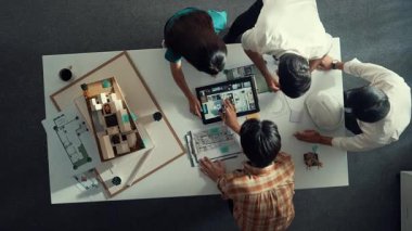 Mimar mühendis ekibinin tartıştığı ve tablet görüntüleme inşaatını planlı ve ev modeliyle toplantı masasında işaret ettiği en tepeden aşağı bakış açısı. Çeşitli tasarımcı tasarım evleri. Hizalama.