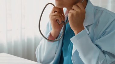 Hasta klinikte ya da hastane ofisinde doktor randevusuna gidiyor. Hastaların nabzını steteskopla kontrol edip risk faktörünü belirleyen doktor semptomları inceliyor. Panorama. Katı.