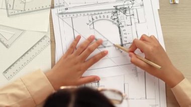 Akıllı mimar ya da akıllı mühendisin ölçüm aracı ve ahşap kalem el kullanarak mimari ofisindeki inşaat isabetinin planının detaylarını yazdığı bir video. Eline odaklan. Tanımlama.