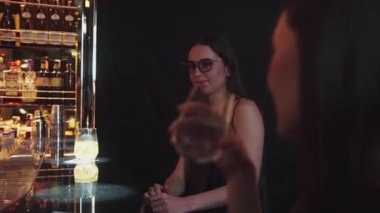 Parlak gece partisinde lüks bir gece kulübünde özel içkide gözlüklü güzel bir kadının portresi. Barda oturmuş, barmen ve arkadaşlarıyla atmosfer partisi saatleri hakkında konuşuyor. Vinosity.