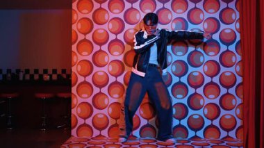 Asyalı break dansçı serbest stile geçiyor ve balon arka planlı kameraya bakıyor. Profesyonel hippi gündelik kıyafet giyer ve gözlük takar. Mutluluk.