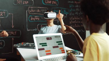 Kafkasyalı kız tahtada mühendislik kodlarıyla otururken Afrikalı erkek programlama sistemi. Liseli kız STEM teknolojisinde VR ya da kulaklık takıyor. Öğretim.
