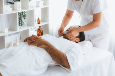 Kaplıca salonunun sakin, modern gündüz atmosferi. Kadın müşteri yüz maskesi takarak kendini yenilemeye çalışıyor. Yüz bakımı ve güzellik kozmetolojisi prosedürü. Sessiz.