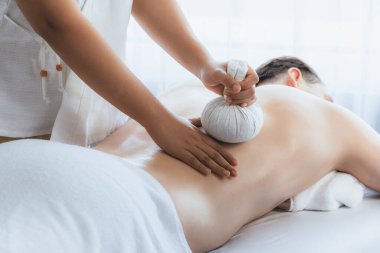 Sıcak bitkisel top spa masaj vücut tedavisi, masör erkek vücuduna nazikçe şifalı bitki torbası bastırıyor. Aromaterapi dinlenme sükuneti ve sükuneti kaplıca salonundaki atmosferi aydınlatıyor. Sessiz.