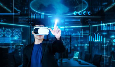VR gözlüklü bir proje yöneticisi mali tabloyu ve ofisteki parlak mavi ışığı gösteriyor. Yetenekli iş adamı artırılmış gerçeklikten elde edilen verileri kullanarak pazarlama stratejisini kontrol edip planlıyor. Yaratıcılık.