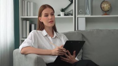 Psikiyatri ofisinde ya da terapi odasında kol koltuğunda oturan profesyonel bir kadın psikolog. Arkadaş canlısı ve ilkel ruh sağlığı danışmanı ve terapisti.