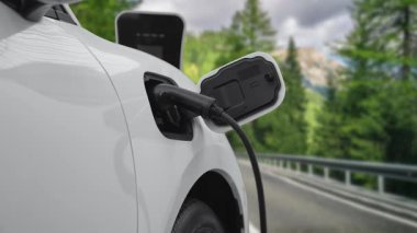 Elektrikli araç konsepti, yeşil çevre için yenilenebilir ve temiz enerjiyle çalışan EV otomobilinin varış noktasına ulaşmadan önce ormandaki şarj istasyonunun enerjisini şarj etmek için durur..