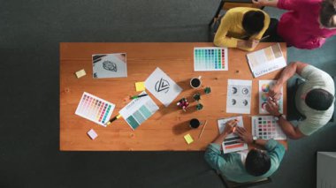 Proje yöneticisi renk paletleri seçerken tasarımcının tablete baktığı yukarıdan aşağıya hava görüntüsü. Profesyonel grafik tasarımının en üst görüntüsü ve logoya bakın. Yetenekli ekip grafikleri seçiyor. Sempozyum.