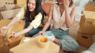 Çekici bir oda arkadaşı oturma odasında paket paketlerken pakette konum yazıyor. Mutlu satıcı birlikte çalışıyor ve teslimat paketini hazırlıyor. Girişimci kargo kutusu paketliyor. Myrmidon.