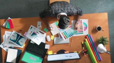 Kulaklıktan müzik dinlerken yetenekli iç dizayn grafiklerinin yukarıdan aşağı havadan görüntüsü. Proje yöneticisi kulaklıkla çalışırken ve rahat şarkılar dinlerken stüdyoda hareket ediyor. Sempozyum.