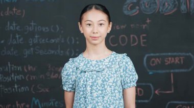 Genç öğrenci başarılı projesini kutlarken kolunu kaldırdı. Mühendislik koduyla karatahtaya bakarken kameraya bakan mutlu genç, STEM sınıfında yazılı. Öğretim