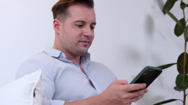 Orta yaşlı bir adam oturma odasındaki koltukta oturur telefon arama verilerini kullanır çocukları iyi bir yetişkin baba ya da eğlence olarak yetiştirir. İşadamı teknolojiyi kolaylık için kullanır. Uyumsuzluk.