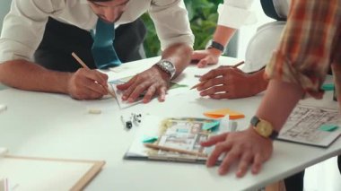 Akıllı iş adamlarının tasarımı planlamak için tabletten proje planına bakarken ve planlar ve toplantı masasındaki bina inşaatı hakkında tartışırken birlikte çalışması. Hizalama.