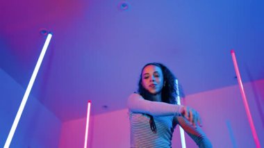 Latin dansçıların kameraya bakıp şehrin pop müziğiyle dans ettiği düşük açılı kamera. Profesyonel çekici hipster, mor veya neon ışıklı hip hop şarkısına geçiyor. Şık bir kumaş. Mutluluk.