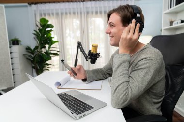 Sunucu kanalı, gülümseyen akıllı yayıncı kaydı, senaryosu ve akıllı telefonuyla sosyal medyada sohbet programı, kulaklık takarak modern ev stüdyosundaki video flamalarını kaydediyor. Bireysel.