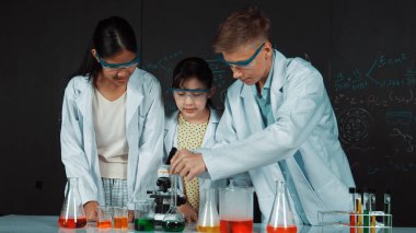 Zeki kız deney yapmak için heyecanlanan çeşitli öğrenciler iken beher kabına renkli solüsyon döker. Profesyonel bilim adamı kimyasal teoriyle kara tahtada deney yapmaya hazırlanıyor. Öğretim.