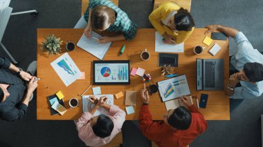 Akıllı iş adamlarının en iyi görüşü pazarlama fikrini toplantıda sunarken, bir grup yatırımcı da hisse senedi piyasası şeması veya veri analizine bakarken strateji dinleyip planlıyorlar. Üst Manzara. Cemaat.