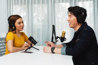 Gülümseyen radyo etkili sunucusu kulaklık takıyor kadın konuşmacı ile röportaj yapıyor sosyal medya internet sitesinden dinleyicilere bilgi paylaşıyor stüdyo kaydında sabah canlı yayın kanalı. İnfobahn.