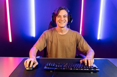 Kazanmak için çevrimiçi oyun oynayan akıllı flama makinesinin sunucu kanalı, neon ışıklı odada seçilen takım yarışması için izleyicilerle birlikte canlı yayında canlı yayında kulaklık takıyor. Bireysel.