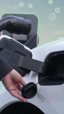 İlerleyen yeşil şehir ESG sembolü, elektrikli araçla birlikte. İş adamı EV arabalarını şarj etmek için şarj aletini şarj ediyor. Şehirdeki şarj istasyonunda ekolojik ve yeşil semboller var..