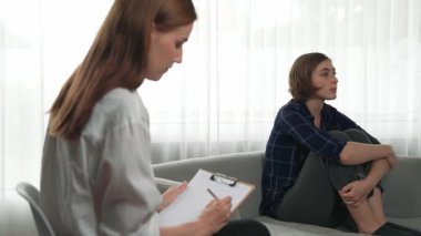 Psikologla ruh sağlığı terapisi gören üzgün travma sonrası stres bozukluğu olan bir kadın. Yaşam sonrası depresyon veya keder. Hayal kırıklığına uğramış genç bir kadın klinikteki duygular hakkında prim psikoloğuyla konuşuyor.
