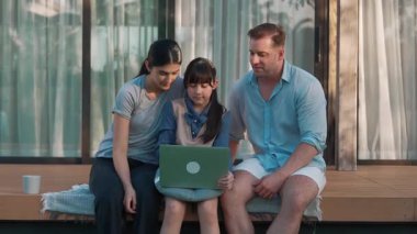 Sevimli baba, anne ve kızı birlikte evin dışındaki balkonda oturuyorlar. Ebeveynler, çevre farkındalığıyla ilgili genç nesli iletişim kurmak için açık hava aktivitelerini kullanırlar. Uyumsuzluk.