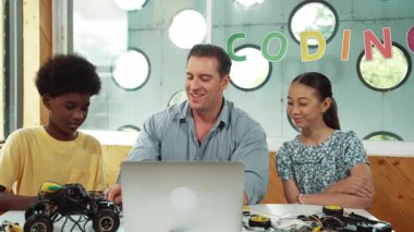 Yakışıklı öğretmen, sofrasında araba modeli ve panosu olan bir dizüstü bilgisayar kullanarak elektronik ekipmanı açıklıyor. Çok kültürlü çocuklar BTMM sınıfında araba modeli yapısını anlatırken öğretmenlerini dinlerler. Öğretim