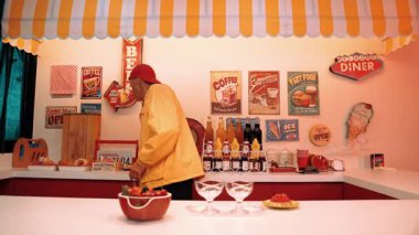 Çekici bir restoran çalışanı, hip hop müziğine taşınırken müşterilere yemek servisi yapmaya hazırlanıyor. Kafkasyalı garson yemek barının arkasında dikilirken serbest stil dans ediyor. Komik dans. Mutluluk.