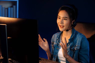 Sunucu kanalı Asyalı etkileyicisi canlı yayında konuşuyor. Sosyal medyada kulaklık takıyor, bilgisayar kaydı yapıyor, dinleyicileri selamlıyor ve Neon Modern Stüdyoları 'nda online olarak koçluk yapıyor. Taktik.