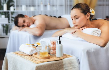 Lüks tatil köyündeki kaplıca salonunda sıcak taş masajı. Gündüz dinginliği ortam, mutlu çift müşterileri bazalt taşı masajının keyfini çıkarıyor. Rahatlatıcı bir sıcaklıkla vücudun üzerinde süzülüyorlar. Sessiz.