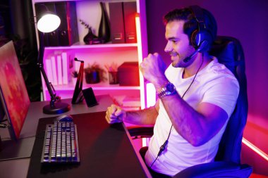 Çevrimiçi oyun oynayan, kulaklık takan, sosyal medyayla oyun oynayan oyuncuya yumruk kaldıran biri. Esport beceri takımı oyuncusu çevrimiçi dijital oyun stüdyosunda. Tahmin et..