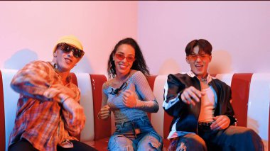 Mutlu kız kameraya bakıyor ve kanepede otururken pop müzik dinliyor. İspanyol kadın serbest stil dans ederken kameraya bakıyor neon ışıkta çeşitli arkadaşlarla dans ediyor. Mutluluk.