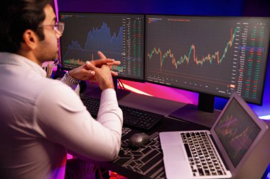 Akıllı tüccar işadamı, karanlık oda gecesinde neon ışıklı ofisteki arama pazarında yüksek kârla ekranda bilgisayar ve bilgisayar üzerinde dinamik borsa yatırımları üzerinde yoğunlaşıyor. Tahmin et..