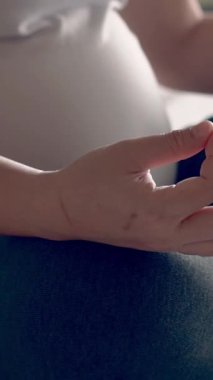 Hamile bir kadın, çocuğuna bakarken yatak odasında yoga egzersizi yapıyor. Hamile karnında bebek tutan mutlu, genç bir anne. Doğum öncesi bakım ve hamilelik.