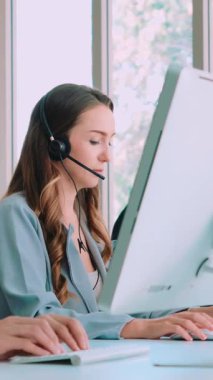 Ofiste çalışan kulaklık takan işadamları uzak müşteri ya da meslektaşlarını desteklemek için çalışıyorlar. Arama merkezi, tele pazarlama, müşteri destek acentesi telefon görüşmesinde hizmet sunar.