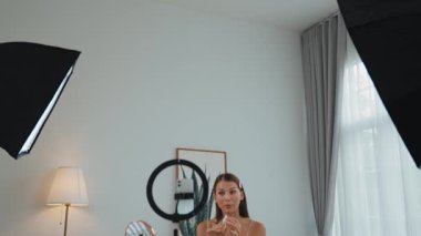 Sosyal medya için güzellik ve kozmetik video içeriği hazırlayan genç bir kadın. Güzellik blogcusu kameraya gülümserken seyircilere ve takipçilere güzellik bakımını gösteriyor. Düzenle