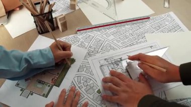 Mimari döküman, ölçüm araçları ve ahşap blokların modern ofiste etrafa saçıldığı masa üzerine planlar yapma konusunda akıllı mimar ve güvenlik mühendisi tartışması. - Yakın çekim. Tanımlama.