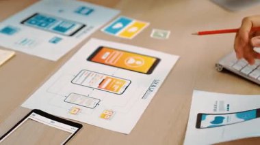 Mobil uygulama için kullanıcı arayüzü prototipini ofis çalışanlarına sunan harika bir şirket çalışanı. UX UI tasarımcısı kağıt üzerinde simge tasarımının işlevini açıklıyor. Sinerjik