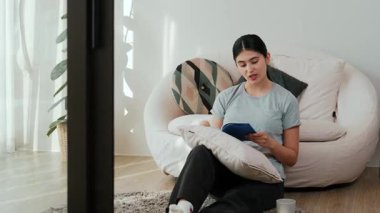 Kanepede oturan orta yaşlı bir kadın, sosyal ve teknolojik mesleki gelişmeler hakkında ders kitabı okur ya da zeki bir anne olmak için çocuk yetiştirir. Hayat boyu öğrenme konsepti. Uyumsuzluk.