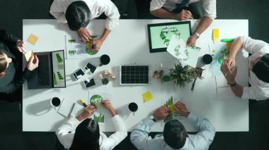 İş adamlarının rüzgar değirmeniyle toplantı masasında temiz enerji ve sürdürülebilir yatırım kullanımı, çevre grafiği ve ahşap ev modeli ile ilgili tartışmalarına tepeden aşağı bakış açısı. Hizalama.