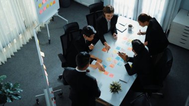 Akıllı yönetici finansal grafiğinin üst görüntüsünden çeşitli takımlara geçerken, bir grup çok kültürlü iş adamı toplantıda hisse yatırım grafiği kullanarak pazarlama stratejisi planlıyorlar. Müdürlük.