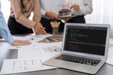 İç mimar tasarımcı grubu, daha kesin tasarım için planlar ve dizüstü bilgisayar ekran mimari yazılımı üzerinde birlikte tartışıyorlar. Modern ev tasarımı ve yenileme. İçgörü