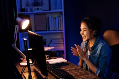 Sunucu kanalı Asyalı etkileyicisi canlı yayında konuşuyor. Sosyal medyada kulaklık takıyor, bilgisayar kaydı yapıyor, dinleyicileri selamlıyor ve Neon Modern Stüdyoları 'nda online olarak koçluk yapıyor. Taktik.