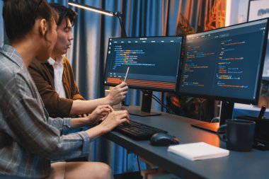 Bilgi teknolojisi geliştiricileri modern ofisteki neon ışık odasında verileri çevrimiçi olarak çalıştıran akıllı web sitesi geliştirme kodlayıcı sistemine işaret ediyorlar. İnfobahn.