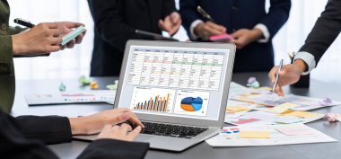 Analizci ekibi yaratıcı ve analitik beyin fırtınası fikri için bilgisayar ekranında BI veri paneli olan yapışkan bir not kullanıyor. Pazarlama stratejisi için finansal veri görselleştirme teknolojisini analiz et. Dahi.