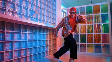 Komik break dansçı kameraya bakarken hiphop 'a doğru serbest adım atıyor. Çılgın mutlu hipster dans edip sokak dansı yaparken Led ışığında günlük kıyafet ve güneş gözlüğü takıyor. Mutluluk.