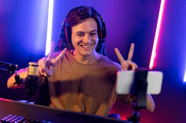 Oyun kanalı, online oyun oynayan akıllı flamalı oyun sunucusu, kulaklık takan, neon ışıklandırma odasındaki takım oyuncusuyla akıllı telefondan canlı yayında konuşan izleyiciler. Bireysel.