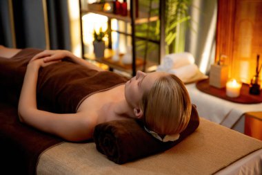 Beyaz kadın müşteri stres önleyici spa masajının keyfini çıkarıyor ve lüks otel ya da otelde sıcak mum ışığında güzellik teniyle eğleniyor. Sessiz.
